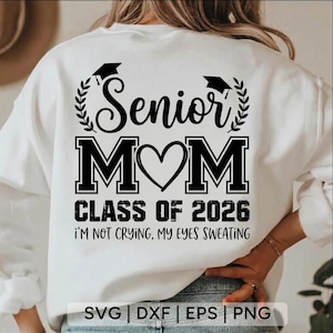 Op de afbeelding: Witte sweatshirt met een zwarte opdruk met de tekst "Senior Mom" boven "Class of 2026". De tekst "I'm not crying, my eyes sweating" staat eronder. Een afstudeerhoed en lauwerkrans sieren het woord "Senior".