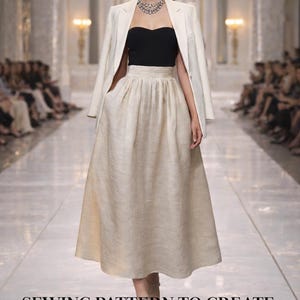 Peut inclure: Une femme défile sur un podium, vêtue d'un haut noir, d'une jupe en lin crème et d'un blazer blanc. Le texte "SEWING PATTERN TO CREATE A LINEN SKIRT" est visible. La jupe est de longueur midi.