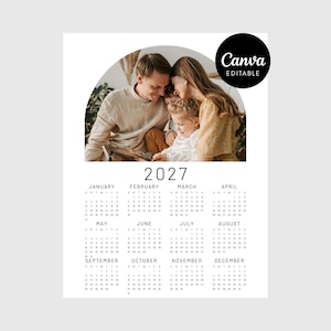 Op de afbeelding: Een kalender voor 2027 met een familiefoto bovenaan. De kalender heeft een minimalistisch ontwerp met het jaar en de maandnamen in een eenvoudig lettertype. Het Canva Editable-logo staat rechtsboven.