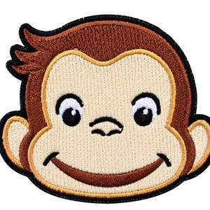 Puede incluir: Un parche bordado que muestra la cara de un mono de dibujos animados con pelaje marrón, cara color crema y ojos grandes. El diseño incluye un borde negro cosido, una boca ancha sonriente y un pequeño mechón de pelo en la parte superior izquierda.