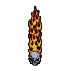 May include: An embroidered patch featuring a light gray skull at the base with a tall, vertical flame design extending upward. The flames are rendered in vibrant shades of yellow, orange, and red, outlined in black against a dark background.