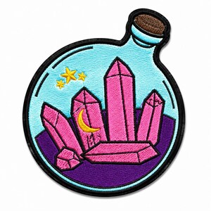 Può includere: Una toppa ricamata a forma di bottiglia di vetro rotonda con un tappo di sughero marrone. All'interno della bottiglia azzurra ci sono diverse formazioni di cristalli rosa, una luna crescente gialla e tre piccole stelle gialle su base viola.