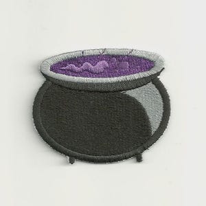 Op de afbeelding: Een geborduurde patch met een zwarte ketel met een brede, grijze rand. De binnenkant van de ketel is gevuld met een levendige paarse vloeistof, weergegeven met een wervelend, gestructureerd steekpatroon dat borrelende beweging suggereert.