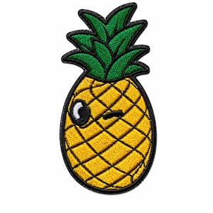 Könnte beinhalten: Ein gestickter Aufbügler in Form einer Ananas mit gelbem Körper und grünen Blättern. Die Ananas hat eine schwarze Stickumrandung und ein zwinkerndes Gesicht mit einem weißen Auge und einer schwarzen Pupille, vor einem schlichten weißen Hintergrund.
