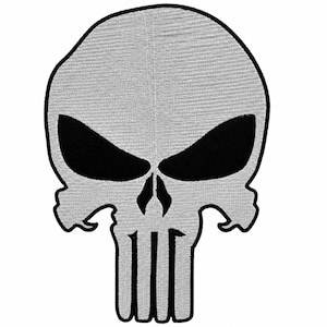 May include: An embroidered patch featuring a stylized skull design with a light gray surface and bold black outlines. The skull has large, almond-shaped black eye sockets and a vertical nose cavity, with a jawline composed of four distinct rectangular teeth.