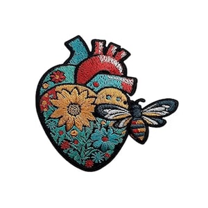 Puede incluir: Parche bordado con un diseño de corazón estilizado, lleno de flores coloridas y un girasol. Una abeja está posada en el lado derecho. El parche tiene un borde negro y es adecuado para ropa o accesorios.