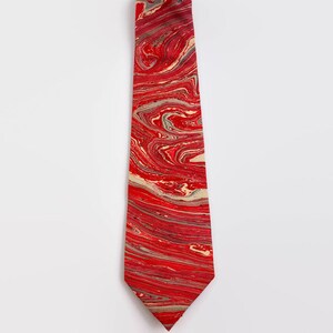 May include: A red tie with a marbled pattern in shades of red, white, and gray.