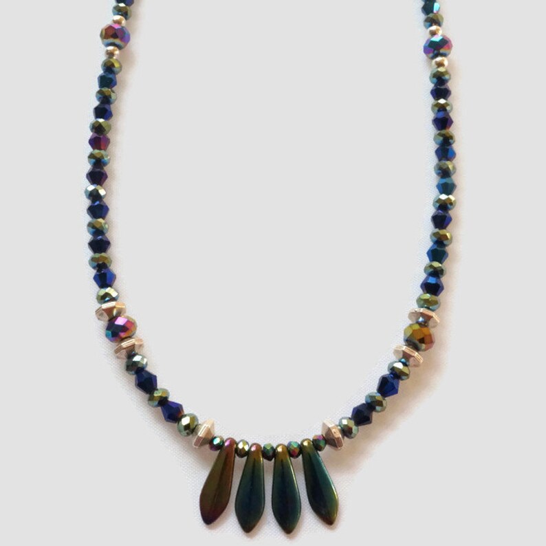May include: A necklace made with iridescent blue and silver beads with a pendant of five iridescent green teardrop-shaped beads.