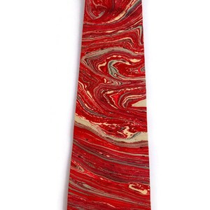 May include: A red tie with a marbled pattern in shades of red, cream, and gray.