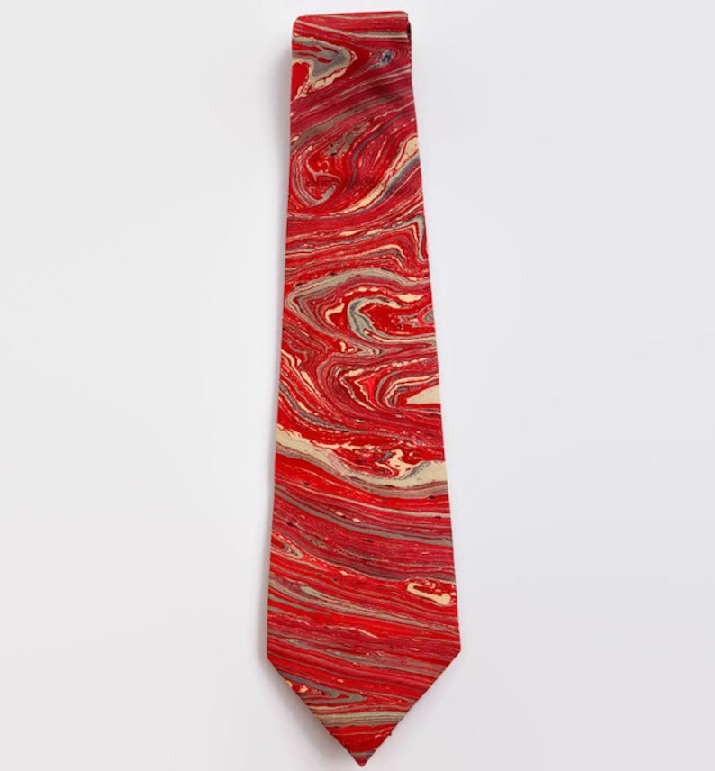 May include: A red tie with a marbled pattern in shades of red, white, and gray.