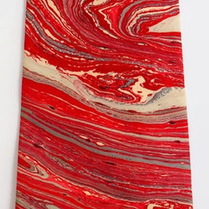May include: A red and cream tie with a marbled pattern. The tie has a pointed tip and is made of a smooth fabric.
