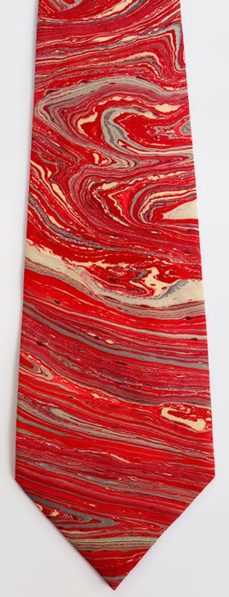 May include: A red and cream tie with a marbled pattern. The tie has a pointed tip and is made of a smooth fabric.
