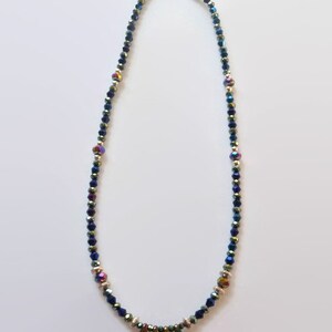May include: A blue iridescent crystal necklace with a gold clasp and a pendant of four iridescent metal leaves.