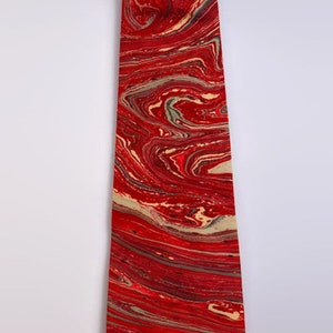 May include: A red tie with a marbled pattern in shades of red, cream, and gray.