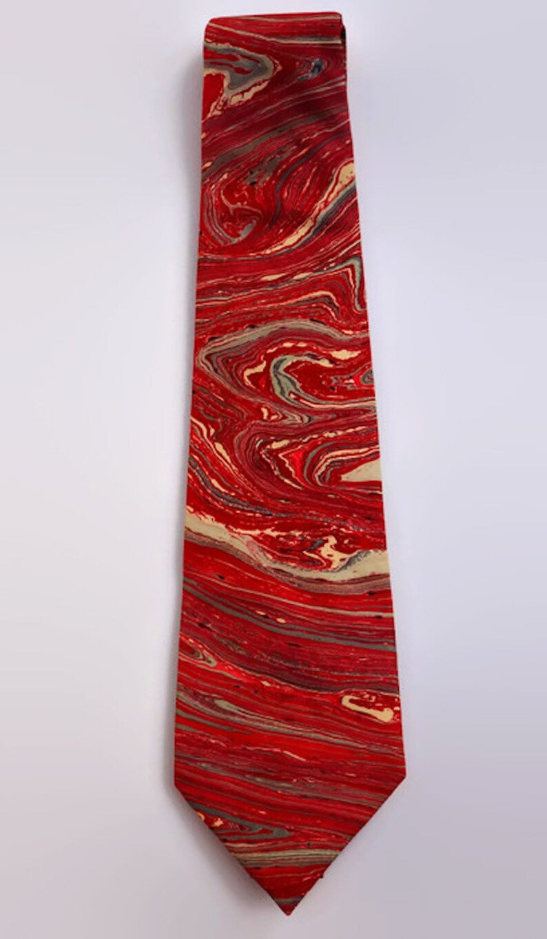 May include: A red tie with a marbled pattern in shades of red, cream, and gray.