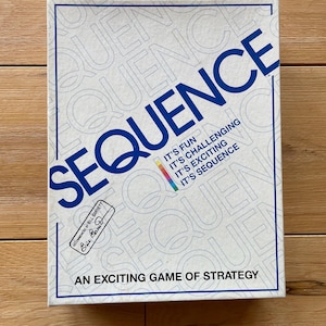 May include: A white box with blue lettering for the board game Sequence. The box has the game's name, "SEQUENCE", in large blue letters. The text "IT'S FUN, IT'S CHALLENGING, IT'S EXCITING, IT'S SEQUENCE" is printed in smaller blue letters below the game's name. The box also has the text "AN EXCITING GAME OF STRATEGY" printed in black letters at the bottom. The box has a small white sticker with the text "RECOMMENDED BY BILL BARRETT" and a signature.