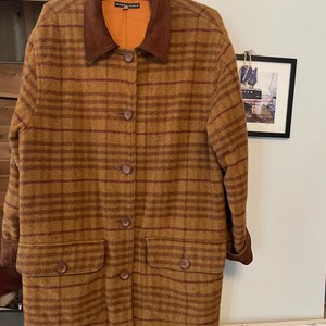 May include: A brown and red plaid coat with a brown suede collar. The coat has a button closure and two pockets.