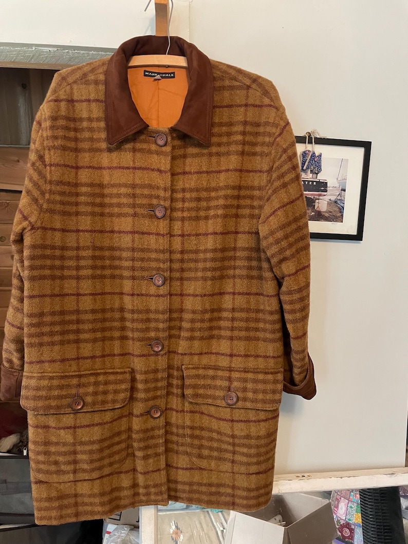 May include: A brown and red plaid coat with a brown suede collar. The coat has a button closure and two pockets.