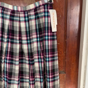 May include: A black, white, pink, and teal plaid skirt with pleats. The skirt has a label that says "PENDLETON".