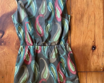 Peut inclure: Robe sans manches avec un fond marron et un motif cachemire dans des tons de rouge, vert et bleu. La robe a une taille ajustée et une fermeture éclair au dos.