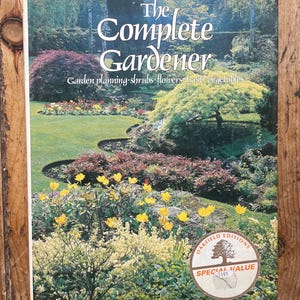 May include: A book titled "The Complete Gardener" with a colorful garden scene on the cover. The cover features a variety of plants, including shrubs, flowers, and trees. The book has a "Special Value" sticker.
