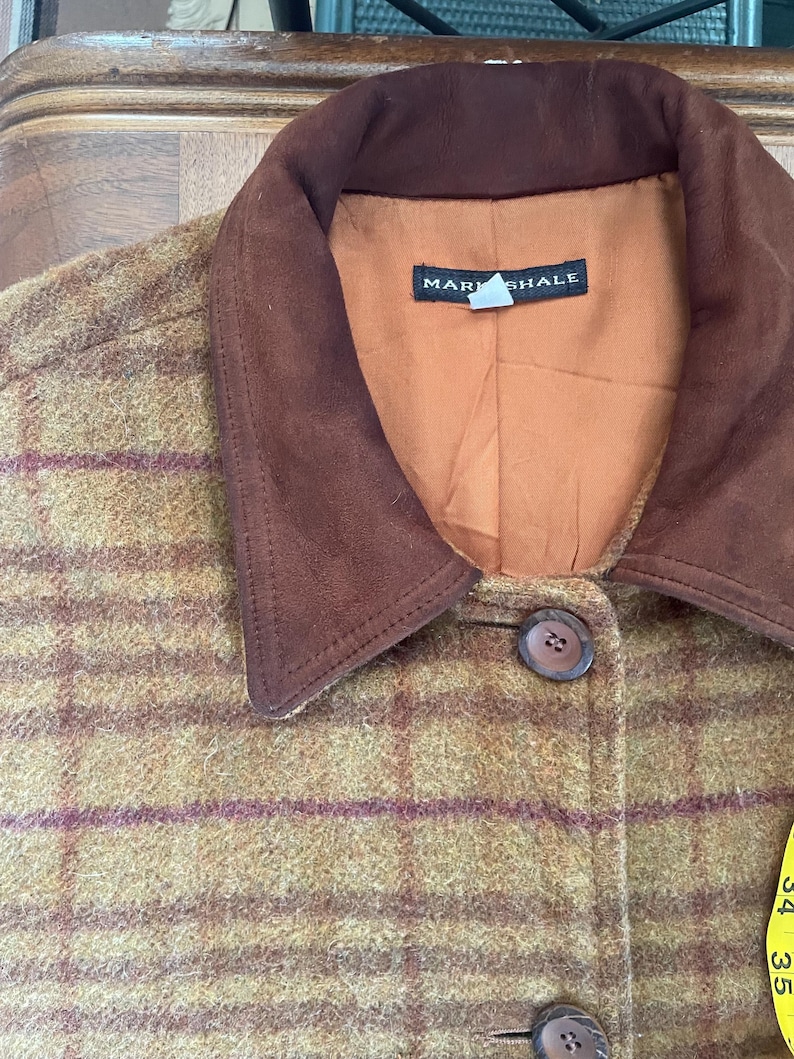 May include: A brown and green plaid jacket with a brown suede collar. The jacket has a label that says "Mark Shale".