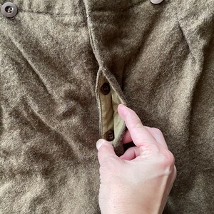 Peut inclure: Gros plan sur l'avant d'un pantalon en laine marron avec une braguette &agrave; boutons. Les boutons sont en plastique marron.