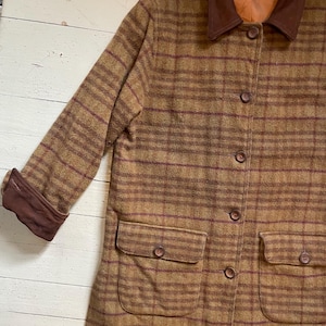 May include: A brown and burgundy plaid jacket with a corduroy collar. The jacket has a button closure and two flap pockets.