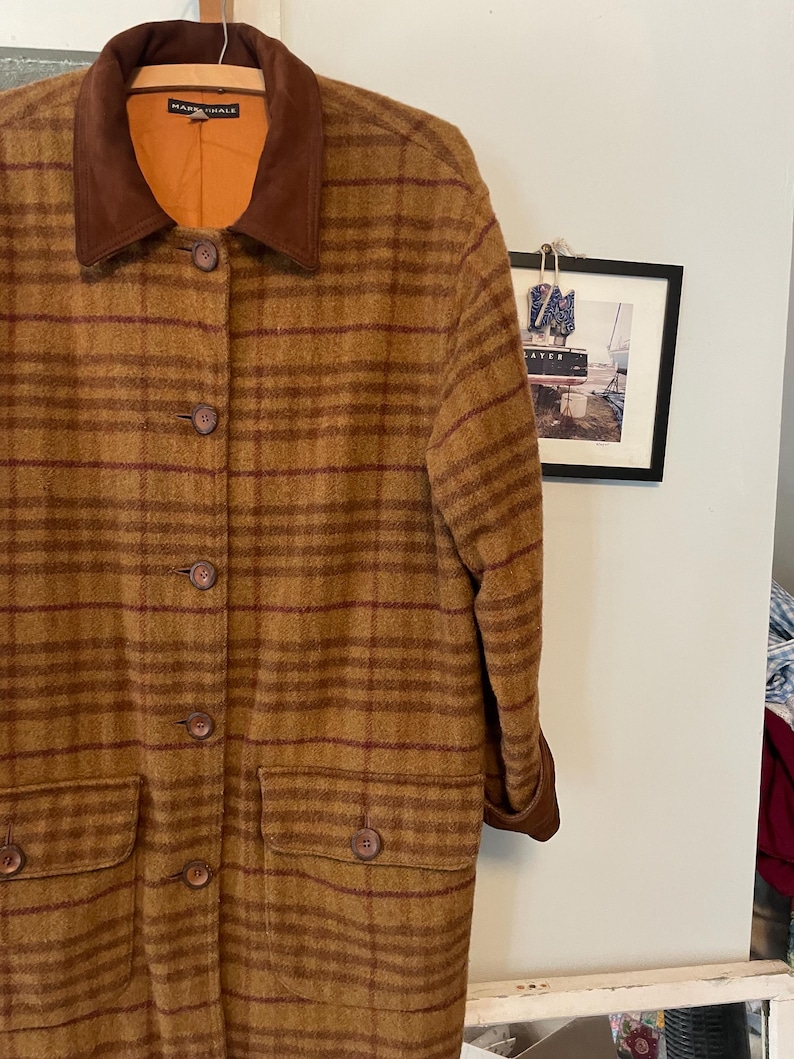 May include: A long brown and red plaid coat with a brown suede collar. The coat has a button closure and two front pockets.