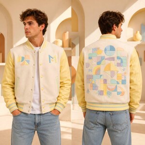 Può includere: Una giacca varsity color crema con maniche gialle e bordi a coste a righe. Il davanti presenta una lettera M e forme geometriche. Il retro mostra un grande e intricato motivo di forme e linee geometriche nei toni in tonalità pastello.