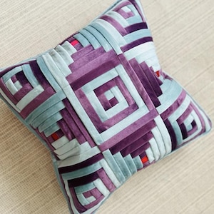 Könnte beinhalten: Quadratisches Zierkissen mit einem geometrischen Muster in Lila-, Blau- und Weißtönen. Das Kissen hat eine weiche, samtige Textur und ein einzigartiges Design. Das Kissen misst ca. 45 cm x 45 cm.