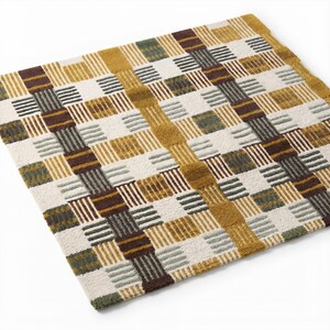 May include: A square rug featuring a geometric grid pattern with a textured, tufted surface. The design consists of alternating blocks and stripes in shades of mustard yellow, dark brown, sage green, and off-white, creating a woven appearance.
