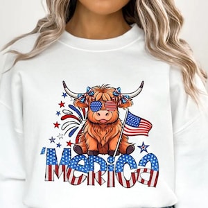 Peut inclure: Sweat-shirt blanc avec un dessin de vache des Highlands portant des lunettes de soleil et un drapeau américain. La vache est décorée en rouge, blanc et bleu. Le mot "'MERICA" est imprimé en dessous.