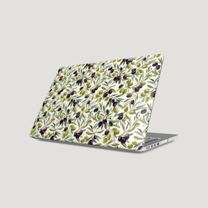 Könnte beinhalten: Ein Laptop mit einer Schutzfolie, die ein sich wiederholendes Muster aus grünen und schwarzen Oliven auf Zweigen mit schmalen, hellgrünen Blättern auf cremefarbenem Hintergrund zeigt und den gesamten äußeren Deckel des Geräts bedeckt.