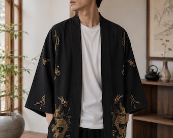 May include: A black open-front kimono-style jacket featuring gold embroidered dragon motifs on the lower panels and geometric line patterns on the upper sleeves. The garment is worn over a plain white crew-neck t-shirt and black trousers.