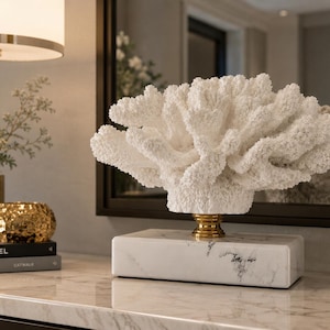 Puede incluir: Una escultura de coral blanco con superficie texturizada, montada sobre una base de mármol con un acento dorado. La escultura es una pieza decorativa para el hogar.