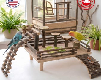 May include: A wooden bird playground featuring a flat platform with a low fence, three elevated circular perches, and two flexible branch ladders. A blue parakeet, a yellow and orange lovebird, and a small finch are perched on the structure.