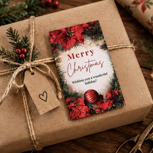 May include: A rectangular gift tag featuring a Merry Christmas greeting, red poinsettias, and a red ornament. The tag is tied with twine to a brown paper-wrapped gift, accompanied by a small kraft paper tag with a hand-drawn heart symbol.