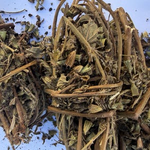 May include: Close-up of dried herbs, showing bundles of brown stems and leaves. The herbs appear to be tied together, presenting a natural, earthy aesthetic. The image highlights the texture and colour variations of the dried plant material.
