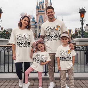 Puede incluir: Cuatro personas vestidas con camisetas crema a juego con un dise&ntilde;o tem&aacute;tico de Disney. El dise&ntilde;o incluye orejas de Mickey Mouse, un castillo y el texto "Disney Family Trip". La familia posa frente a un castillo.