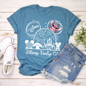 Puede incluir: Camiseta azul turquesa con un dise&ntilde;o de Disney Family Trip. El gr&aacute;fico incluye el nombre "Diana", fuegos artificiales, un castillo y el personaje Stitch. La camiseta se combina con pantalones cortos de mezclilla y zapatillas Converse blancas.