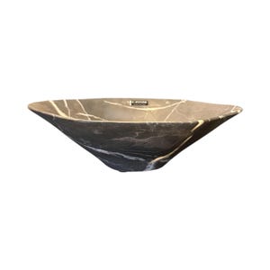May include: A dark gray, stone vessel sink with white veining. The sink has a unique, angular shape with gently sloping sides. The interior is a solid dark gray, and the exterior features a marble-like pattern. The sink is designed for bathroom use.