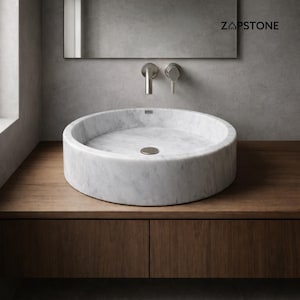 May include: A white marble vessel sink with a circular design. The sink is set on a wooden vanity with a matching cabinet. The faucet is silver and mounted on the wall. The brand name "ZAPSTONE" is visible on the mirror.