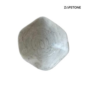 May include: A smooth, rounded, gray and white stone with a swirling pattern. The stone has a polished appearance and a unique, organic shape. The brand name "ZAPSTONE" is printed in black in the upper right corner.