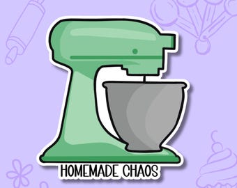 May include: A mint green stand mixer with a grey mixing bowl and a white border. The text "HOMEMADE CHAOS" is printed in black capital letters at the base of the mixer. The design features a flat, graphic illustration style with bold outlines.