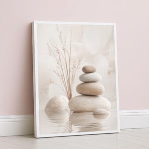 May include: A framed canvas print depicting a stack of smooth, beige stones, with a few sprigs of dried grass. The stones are reflected in the water below, creating a serene and minimalist aesthetic. The background is a soft, neutral colour.