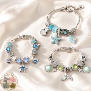 Könnte beinhalten: Drei silberfarbene Bettelarmbänder mit blauen, grünen und schillernden Perlen sowie Anhängern in Form von Seesternen, Muscheln und Meerjungfrauenschwänzen. Eine kleine kreisförmige Grafik zeigt den Text Custom Bags und verschiedene Beutel.