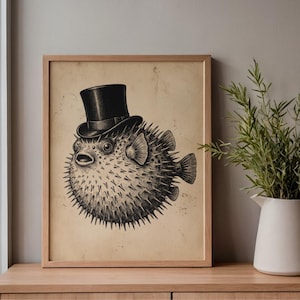 May include: A framed print featuring a detailed black and white illustration of a pufferfish wearing a black top hat. The artwork has a vintage aesthetic, set against a tan background, and is displayed in a light brown wooden frame.