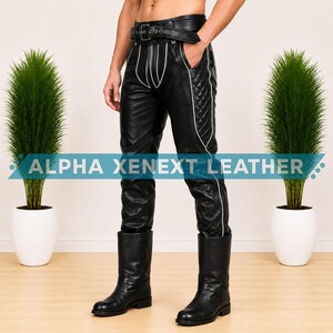 May include: Black leather pants featuring a quilted side panel, white piping accents, and an integrated belt with a metal buckle. The pants display the text ALPHA XENEXT LEATHER across the front. The garment is paired with black leather boots.