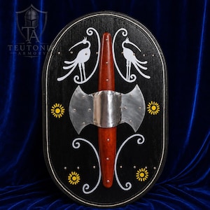 May include: An oval black wooden shield featuring a central vertical reddish-brown wooden spine with a metallic silver axe-shaped boss. The surface is decorated with white painted crane illustrations, yellow floral motifs, and silver rivets.
